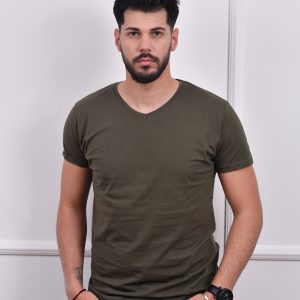 Maslinasta muška majica sa V izrezom, u kombinaciji sa crnim farmerkama, s rukama u džepovima