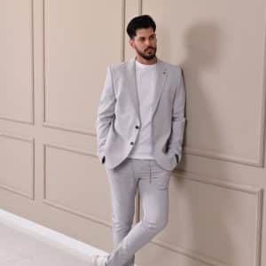 Muško odelo u svetlosivoj nijansi, kombinovano sa klasičnom belom majicom i patikama, pruža moderan i opušten izgled idealan za smart-casual prilike.