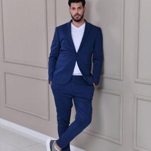 Tamno plavo muško odelo sa slim fit krojem, modernog dizajna, u kombinaciji sa belom majicom i sportskim tenisicama za elegantan, ali opušten izgled.