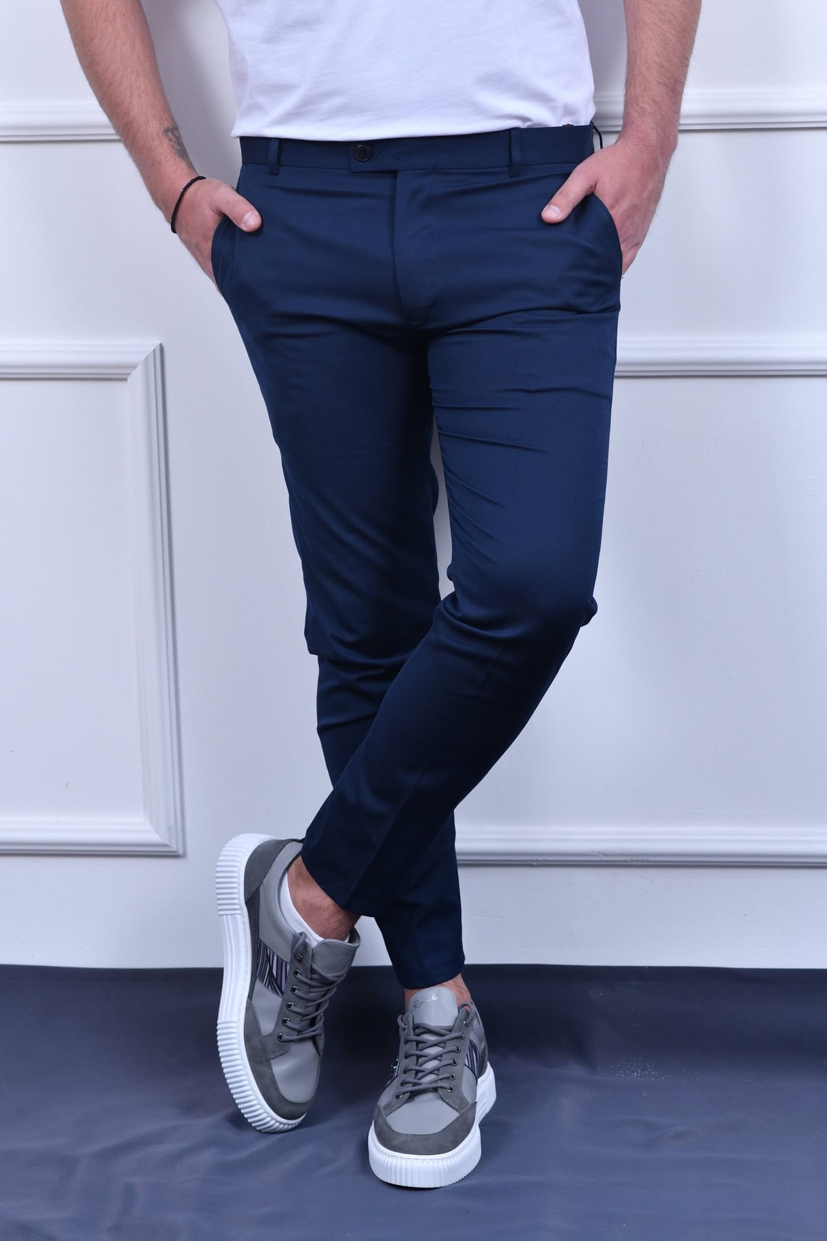 Plave slim fit pantalone sa modernim džepovima, u kombinaciji sa sportskom obućom.